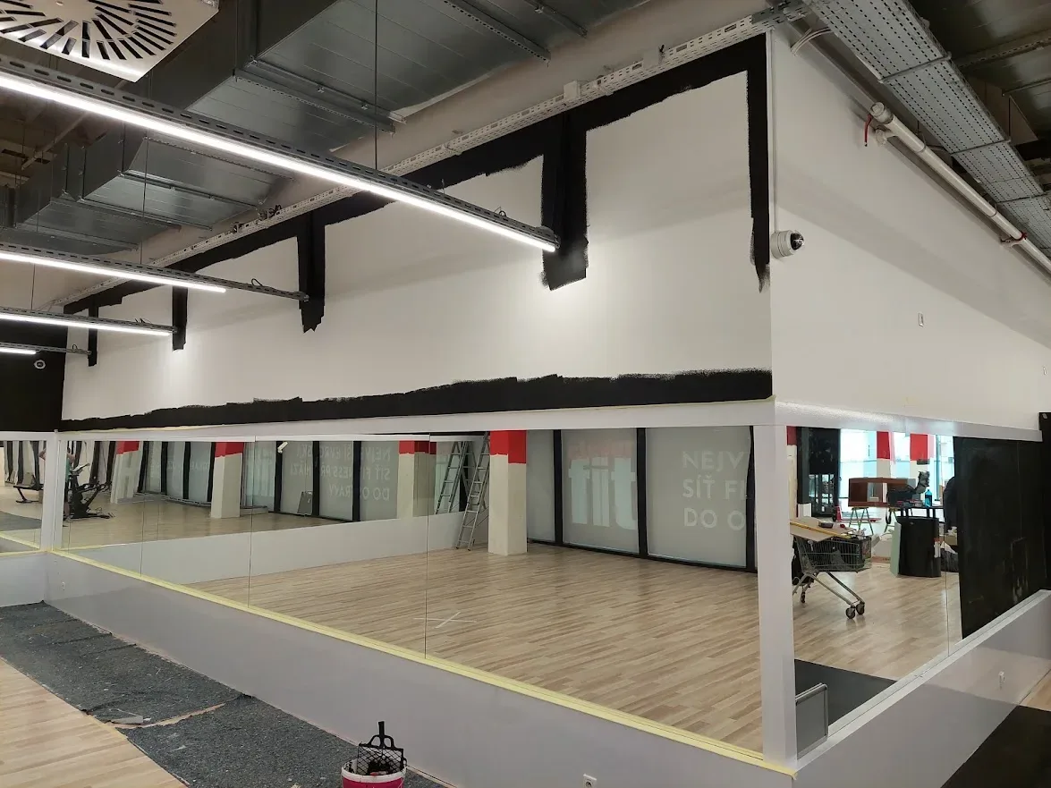 Sála fitnescentra so zrkadlovou stenou na začiatku maľovania