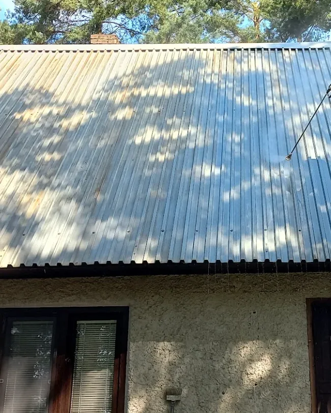 Maliar na rebríku pri nástreku plechovej strechy
